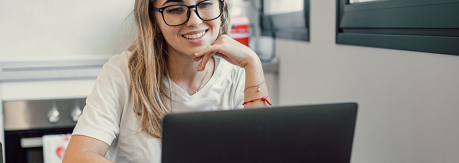 Happy young blonde business woman entrepreneur using computer looking at screen working in internet sit at office desk, smiling millennial female professional employee typing email on laptop workplace